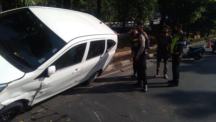 Mobil terguling usai tabrak separator jalan di Depok (Rizky/detikcom)