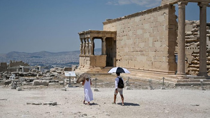 1242087223 Turis di Acropolis, Athena kepanasan saat suhu udara mencapai 42 derajat celsius pada 24 Juli 2022. (Louisa Goulimaki/AFP via Getty Images)