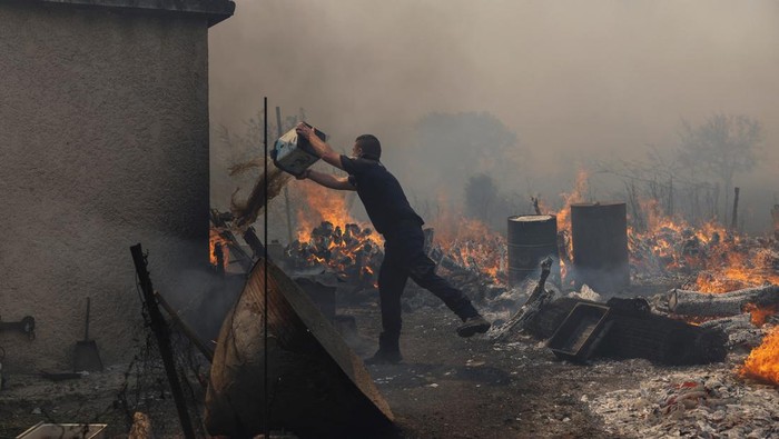 Kebakaran Hutan Hanguskan Sejumlah Rumah di Pulau Lesbos, Yunani A police officer tries to extinguish wildfire burning in the village of Vatera, on the island of Lesbos, Greece July 23, 2022. REUTERS/Alexandros Avramidis