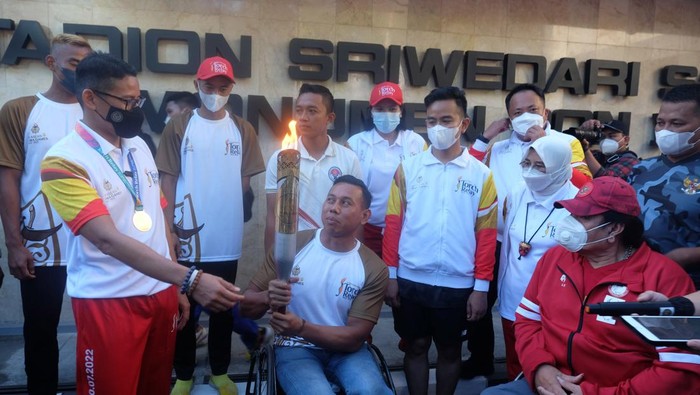 Momen Sandiaga Uno-Gibran Ramaikan Pawai Obor ASEAN Para Games Atlet cabor para atletik National Paralympic Committee (NPC) Indonesia Jaenal Aripin (tengah) membawa api obor disaksikan Menteri Pariwisata dan Ekonomi Kreatif (Menparekraf) Sandiaga Uno (kiri), Wali Kota Solo yang juga Ketua INASPOC 2022 Gibran Rakabuming Raka (ketiga kanan) dan Ketua umum National Paralympic Committee (NPC) Indonesia Senny Marbun (kanan) saat torch relay atau pawai obor ASEAN Para Games 2022 di Stadion Sriwedari, Solo, Jawa Tengah, Minggu (24/7/2022). Indonesia menjadi tuan rumah ajang ASEAN Para Games XI 2022 yang akan mempertandingkan 14 cabang olahraga dan diikuti 11 negara-negara Asia Tenggara pada 30 Juli-6 Agustus 2022 mendatang. ANTARAFOTO/Maulana Surya/foc.