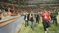 Usai peresmian JIS, Anies berjalan di pinggir lapangan untuk kembali ke tribun sambil menyapa penonton konser dan juga The Jakmania.