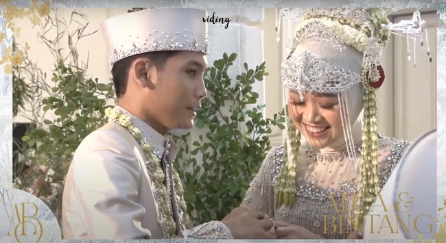Sudah resmi menjadi pasangan suami istri, keduanya pun terlihat saling memasangkan cincin di jari manis satu sama lain. Dalam foto tampak Alca dengan penuh cinta memasangkan cincin di jari manis suaminya. Foto: YouTube/Bintang Emon