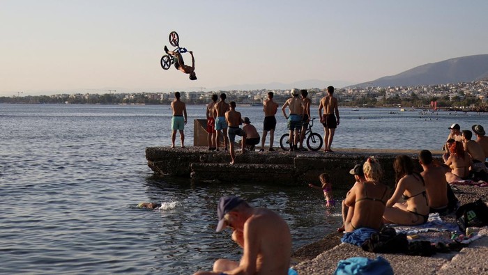 A biker performs tricks at Kavouri beach during a heatwave near Athens, Greece July 24, 2022. REUTERS/Stelios Misinas