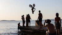 Seorang sepeda melakukan trik di pantai Kavouri, Athena, Yunani, Minggu (24/7/2022).