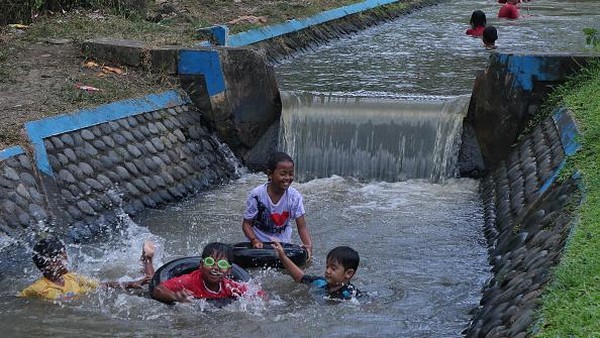 Anak-anak bermain di sebuah sungai di Desa Kebondalem, Banyuwangi, Jawa Timur, Minggu (24/7/2022).  