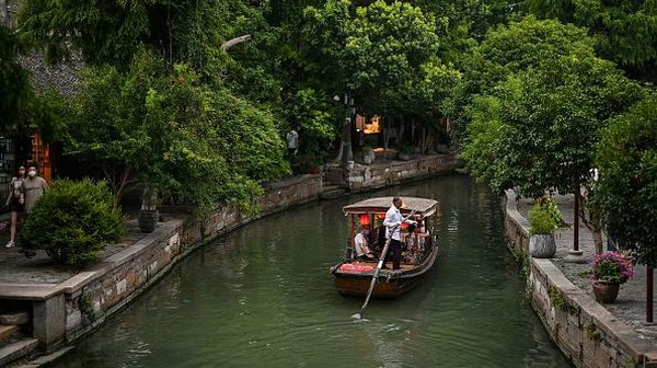Sebuah perahu turis berlayar di sepanjang saluran kota air kuno Zhujiajiao di Shanghai, China, Minggu (24/7/2022). Jika mengunjungi Kota Shanghai, China kurang lengkap rasanya apabila tidak bertandang ke kota air ala Venesia dari timur.   