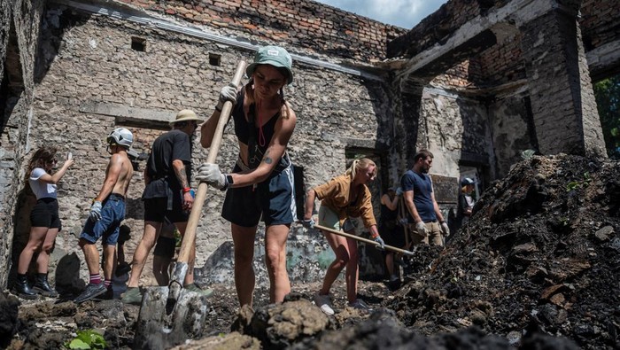 An artist performs while volunteers remove debris from the House of a Culture in the village of Yahidne, which was heavily damaged during Russia's attack on Ukraine, in Chernihiv region, Ukraine July 23, 2022. Members of the volunteers' movement Repair Together travel over regions, which were under Russian occupation and help local residents to clean up damaged buildings under accompaniment of electronic music. REUTERS/Viacheslav Ratynskyi