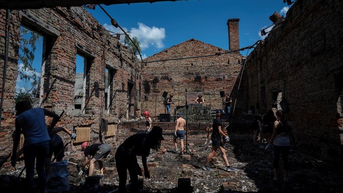 DJ Hibur Relawan yang Bersihkan Puing-puing Akibat Serangan Rusia An artist performs while volunteers remove debris from the House of a Culture in the village of Yahidne, which was heavily damaged during Russia's attack on Ukraine, in Chernihiv region, Ukraine July 23, 2022. Members of the volunteers' movement Repair Together travel over regions, which were under Russian occupation and help local residents to clean up damaged buildings under accompaniment of electronic music. REUTERS/Viacheslav Ratynskyi