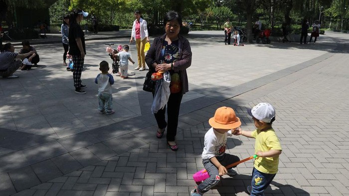 Children play next to adults at a park in Beijing, China June 1, 2021. REUTERS/Tingshu Wang