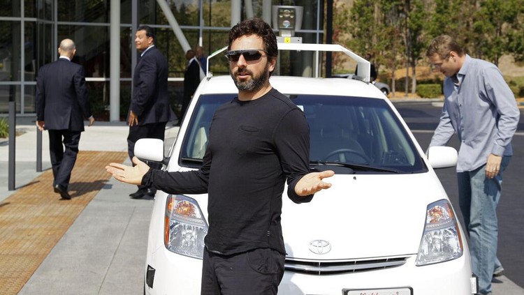 FILE - In this Sept. 25, 2012, file photo, Google co-founder Sergey Brin gestures after riding in a driverless car with officials, to a bill signing for driverless cars at Google headquarters in Mountain View, Calif. Google engineers say they have turned a corner in their pursuit of creating a car that can drive itself. Test cars have been able to navigate freeways comfortably for a few years. On Monday, April 28, 2014, Google said the cars can now negotiate thousands of urban situations that would have stumped them a year or two ago.  (AP Photo/Eric Risberg, File)