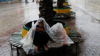 Warga yang kedinginan berlindung dengan plastik dari rintik hujan yang terus turun.