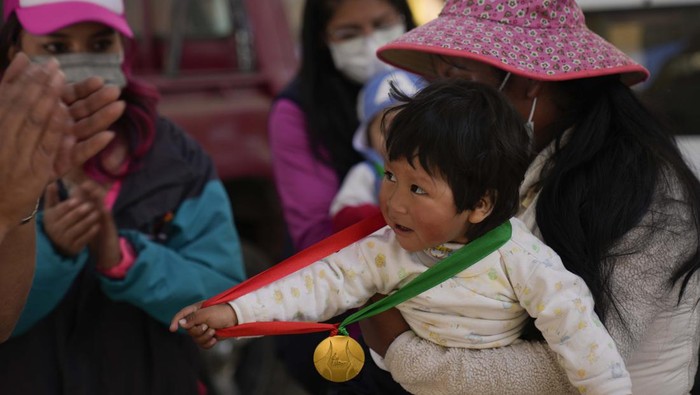 A baby holds his gold medal after winning the baby crawling competition in the Mallasa neighborhood of La Paz, Bolivia, Sunday, July 24, 2022. A dozen babies took part in the competition with a carpet to protect their knees, as moms, dads and grandparents encouraged them. (AP Photo/Juan Karita)