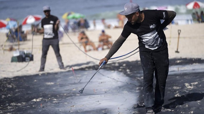 Lukisan Raksasa Lambang Kebersamaan Mejeng di Pantai Brasil A land-art fresco made with biodegradable paint of charcoal, chalk, water and milk proteins, by French-Swiss artist Saype, covers Copacabana beach as part of the artist's worldwide project titled Beyond Walls in Rio de Janeiro, Brazil, Friday, July 15, 2022. The artist said he is creating a symbolic human chain around the world with the aim of promoting togetherness, kindness and openness to the world. (AP Photo/Silvia Izquierdo)