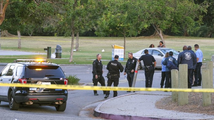 Penembakan Maut di AS Terjadi Lagi, Kali Ini di Taman Los Angeles A police officer interviews a bystander near the scene of a shooting at Peck Park in San Pedro, Calif., Sunday, July 24, 2022. (AP Photo/Ringo H.W. Chiu)