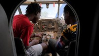 Ernest Ofori Sackitey (28), seniman dan instruktur drone, dan Abdul-Latif Zakaria (16), seorang sukarelawan studio, menjelajahi kokpit pesawat biplan Soviet Antonov AN-2.