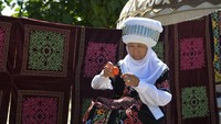 Seorang wanita Kirgistan mengenakan elecheck, hiasan kepala tradisional Kirgistan untuk wanita yang sudah menikah.