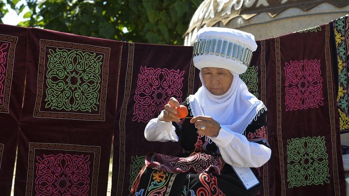 A Kyrgyz woman lays out carpets in front of yurt, traditional Kyrgyz houses during the Ak-Moor Fest Ethno-festival in Ornok, a resort village on the northern shore of Lake Issyk-Kul, 207 kilometers (129 miles) east of Bishkek, Kyrgyzstan, Saturday, July 23, 2022. On the shore of one of the world's largest lakes, high up in Kyrgyzstan's Tian Shan mountains, models strutted and sashayed in outfits mixing the ancient and modern at the World Nomads Fashion festival. (AP Photo/Vladimir Voronin)