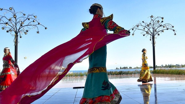 Di tepi salah satu danau terbesar di dunia, tinggi di pegunungan Tian Shan, Kirgistan, para model berjalan mondar-mandir dalam pakaian yang memadukan gaya kuno dan modern di festival Mode Pengembara Dunia.