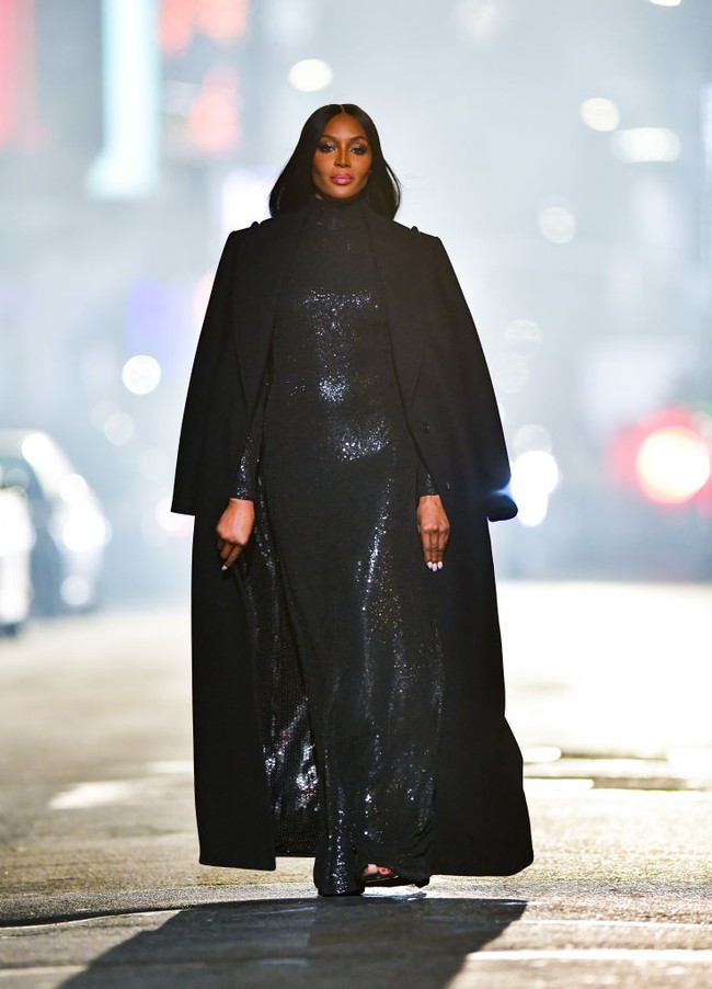 Naomi Campbell mengenakan gaun sequin turtle neck yang dipadukan dengan coat hitam senada gaunnya. Foto: James Devaney/GC Images