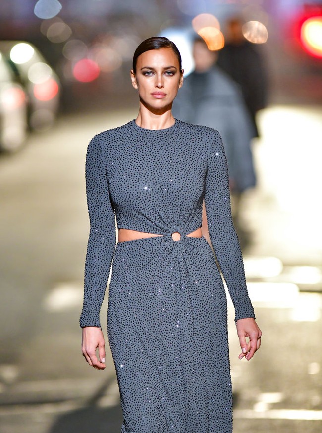 Catwalk di jalanan, top model Irina Shayk tampil memesona dalam gaun midi berwarna abu-abu yang memiliki detail cut out di bagian pinggang. Foto: James Devaney/GC Images
