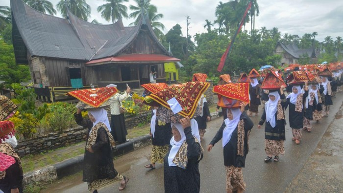 TRADISI BAKAUA ADAT Bundo Kanduang mengikuti arak-arakan sambil menjunjung jamba (dulang berisi makanan) di kepala mereka saat digelarnya prosesi Bakaua Adat di perkampungan adat Nagari Sijunjung, Kabupaten Sijunjung, Sumatera Barat, Senin (25/7/2022). Bakaua adat adalah semacam prosesi tolak bala dan acara menentukan waktu turun ke sawah (masa tanam) secara serentak sekaligus wujud syukur setelah panen sebelumnya. ANTARA FOTO/Iggoy el Fitra/rwa.