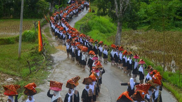 Bundo Kanduang mengikuti arak-arakan sambil menjunjung jamba (dulang berisi makanan) di kepala mereka saat digelarnya prosesi Bakaua Adat di perkampungan adat Nagari Sijunjung, Kabupaten Sijunjung, Sumatera Barat, Senin (25/7/2022).  