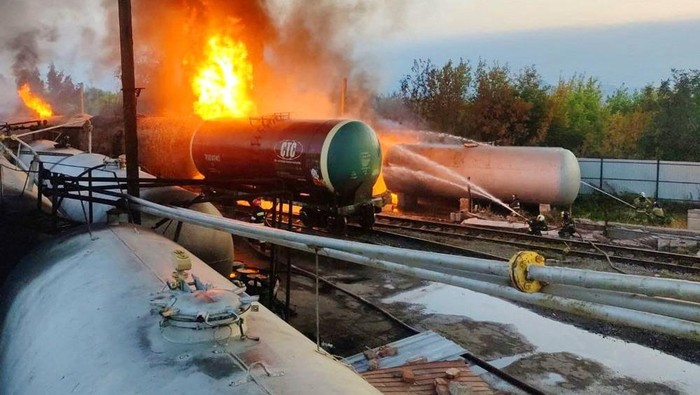 Firefighters gather near tank cars as they work to extinguish a fire at an oil depot in the Budyonnovsky district of Donetsk, Ukraine, in this handout image released by the self-proclaimed Donetsk People's Republic's emergencies ministry July 26, 2022. Press Service of Emergencies Ministry of Donetsk People's Republic/Handout via REUTERS ATTENTION EDITORS - THIS IMAGE HAS BEEN SUPPLIED BY A THIRD PARTY. NO RESALES. NO ARCHIVES. MANDATORY CREDIT.