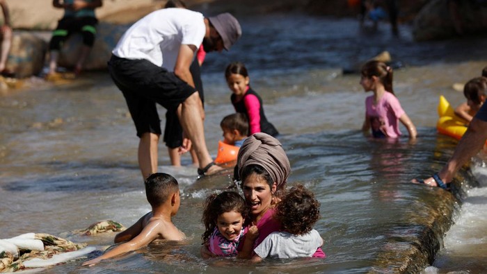 Palestinians and Israel settlers cool off during a heat wave, in al-Oja springs near Jericho in the Israeli-Occupied West Bank July 22, 2022. REUTERS/Mohamad Torokman