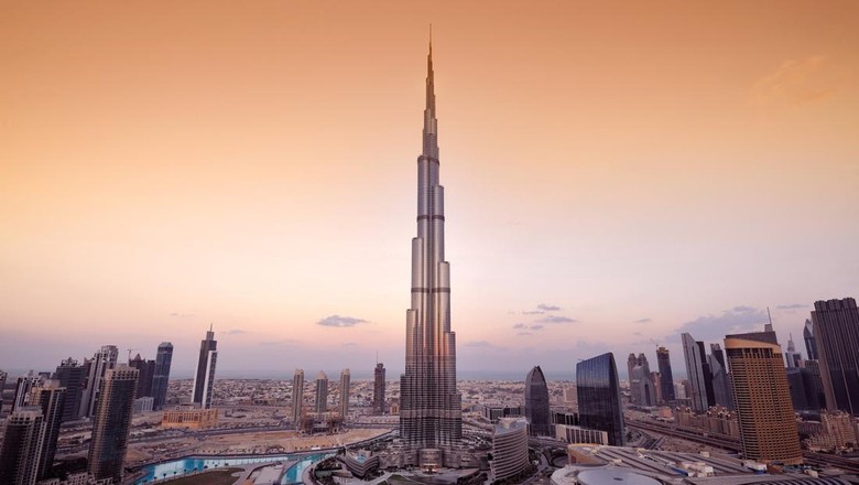 Ilustrasi Gedung Paling Tinggi di Dunia A panoramic view of the Dubai city skyline with the Burj Khalifa shown in the center. The Burj Khalifa is the tallest building in the world.