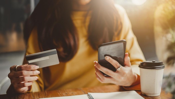 Young beautiful asian woman using smart phone and credit card for shopping online in coffee shop cafe, vintage tone color