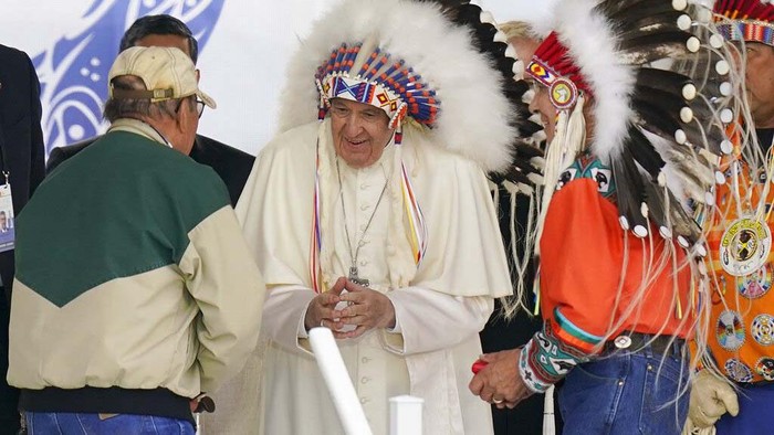 Pope Francis dons a headdress during a visit with Indigenous peoples at Maskwaci, the former Ermineskin Residential School, Monday, July 25, 2022, in Maskwacis, Alberta. Pope Francis traveled to Canada to apologize to Indigenous peoples for the abuses committed by Catholic missionaries in the countrys notorious residential schools. (AP Photo/Eric Gay)