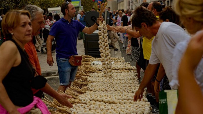 A boy carries strips of garlics during the garlics fair in Vitoria, northern Spain, Monday, July 25, 2022. Every year a traditional garlic market is set on the Saint James patron day in Vitoria gathering producers of all around Spain. (AP Photo/Alvaro Barrientos)