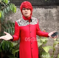 Seperti inilah gaya Marcel saat menyambangi tempat Gus Samsudin. Dia tampil dengan outer merah berpotongan long coat, lengkap dengan wig merah yang selalu ia pakai. Sayangnya, di momen tersebut Pesulap Merah dihadang oleh pengacara dan warga sekitar di sana. Foto: Pesulap Merah. (Foto: tangkapan layar/YouTube Marchel Radival)