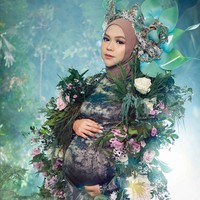 Gaya earthy juga dipilih Ria Ricis dalam konsep pemotretan kehamilan. Wanita 27 tahun ini tampil berbalut gaun motif abstrak bernuansa hijau tua. Tubuhnya tampak dihiasi ornamen bunga dan dedaunan. Foto: Instagram/@fdphotography90 @teukuryantr