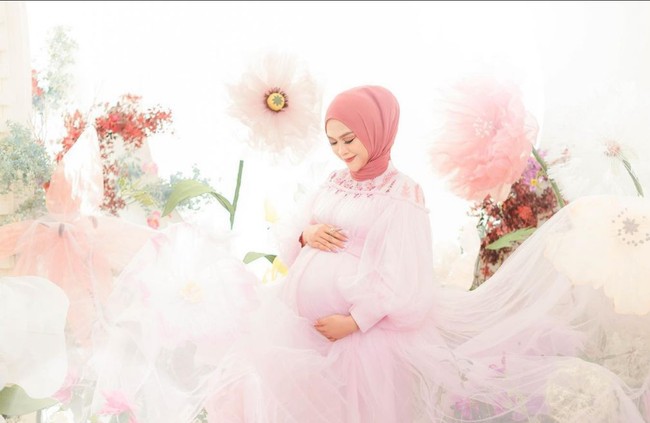 Penampilan Ria Ricis yang berkesan dreamy dengan gaun tulle warna pink serta latar belakang bunga-bunga nan cantik. Foto: Instagram/@fdphotography90 @teukuryantr