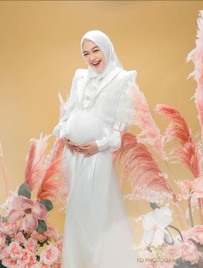 Mengenakan busana dan hijab putih, Ria Ricis kembali memperlihatkan kebahagiaannya dengan tawa lepas. Kali ini ia memadukan gaun panjang dengan bolero putih. Foto: Instagram/@fdphotography90 @teukuryantr