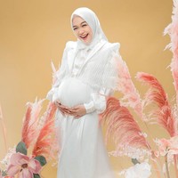 Mengenakan busana dan hijab putih, Ria Ricis kembali memperlihatkan kebahagiaannya dengan tawa lepas. Kali ini ia memadukan gaun panjang dengan bolero putih. Foto: Instagram/@fdphotography90 @teukuryantr