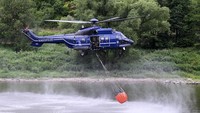 Helikopter polisi federal Jerman hilir mudik untuk mengambil air dari Sungai Elbe. Air dari sungai itu akan digunakan untuk memadamkan kebakaran hutan. Robert Michael/dpa via AP.