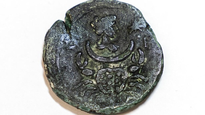 A rare, nearly 1,850-year-old bronze coin discovered off the Israeli coastal city of Haifa is on display at Israel's Antiquities Authority office in Jerusalem, Tuesday, July 26, 2022. The coin bears the image of the zodiac sign Cancer behind a depiction of the moon goddess Luna. Experts said Monday the coin was minted in Alexandria, Egypt, under the rule of the Roman Emperor Antoninus Pius in the second century. The antiquities authority says it is the first time such a coin has been found off the Israeli coast. (AP Photo/Tsafrir Abayov)