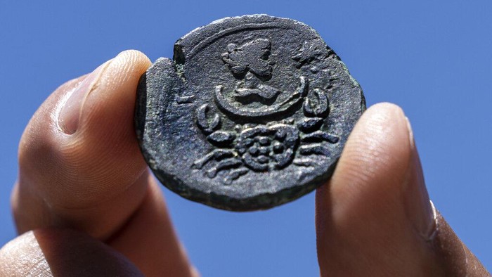 A rare, nearly 1,850-year-old bronze coin discovered off the Israeli coastal city of Haifa is on display at Israel's Antiquities Authority office in Jerusalem, Tuesday, July 26, 2022. The coin bears the image of the zodiac sign Cancer behind a depiction of the moon goddess Luna. Experts said Monday the coin was minted in Alexandria, Egypt, under the rule of the Roman Emperor Antoninus Pius in the second century. The antiquities authority says it is the first time such a coin has been found off the Israeli coast. (AP Photo/Tsafrir Abayov)