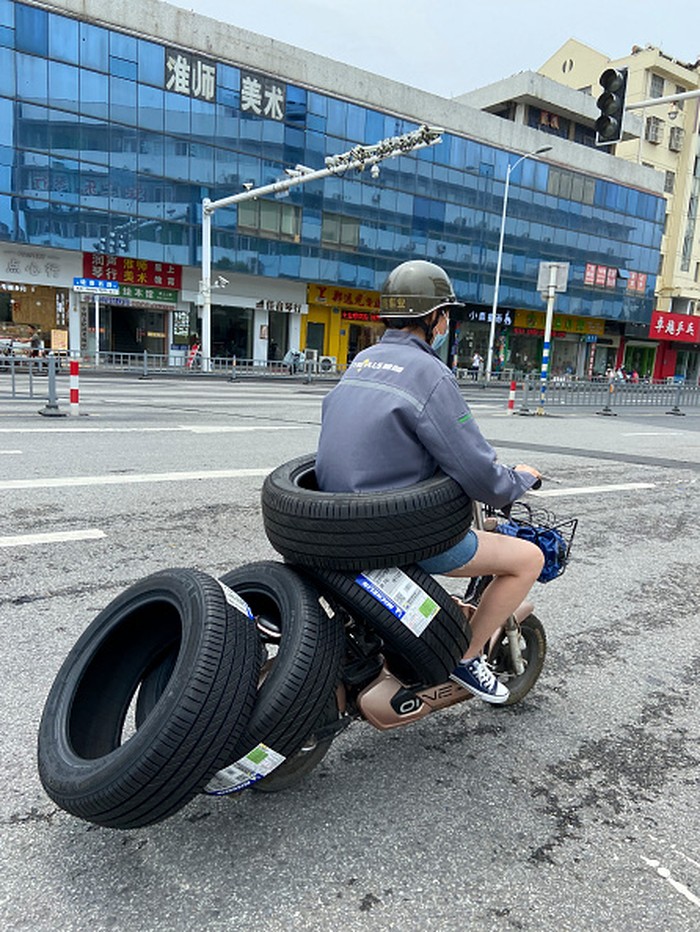 Motor Listrik Ini Punya '6 Roda', 1nya Dipinggang HUAI'AN, CHINA - JULY 26, 2022 - A female electric driver drives slowly with four car tires and a car tire around her waist on a street in Huai 'an, East China's Jiangsu Province, China, July 26, 2022. (Photo credit should read CFOTO/Future Publishing via Getty Images)