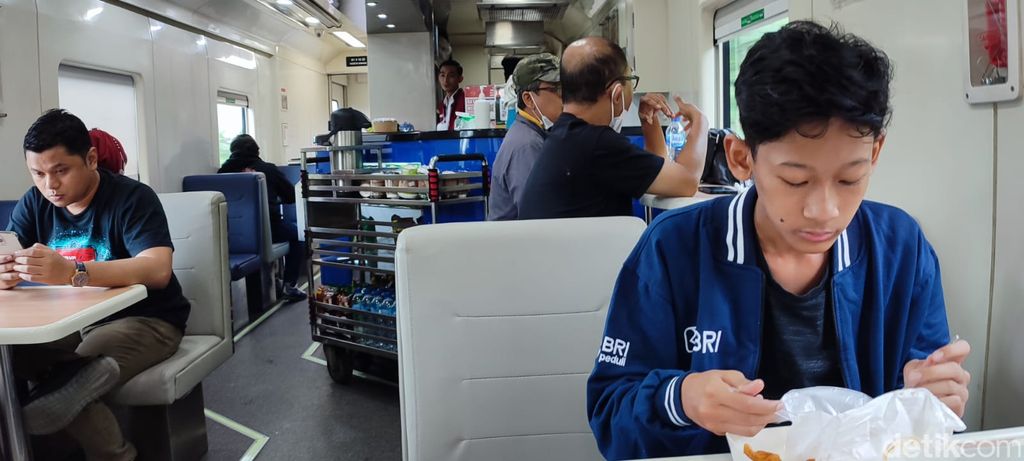 Penumpang yang tengah menikmati santapan dalam gerbong kereta