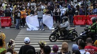 Sejumlah orang di atas trotoar tampak merekam aksi fashion show tersebut.