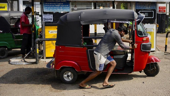 A police officer controls traffic at a fuel station in Colombo, Sri Lanka, Wednesday, July 27, 2022. Sri Lanka's economic crisis has left the nation's 22 million people struggling with shortages of essentials, including medicine, fuel and food. (AP Photo/Eranga Jayawardena)