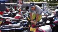 Pria melompat untuk melewati antrean sepeda motor untuk mengisi bahan bakar. Sepeda motor ini lebih terlihat diparkir daripada mengantre karena lamanya waktu tunggu.