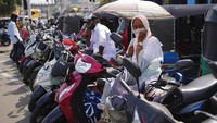 Ibu-ibu yang kepanasan karna menunggu untuk mengisi bensin motornya. 
