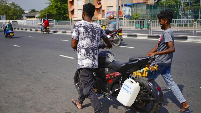 Sri Lanka A police officer controls traffic at a fuel station in Colombo, Sri Lanka, Wednesday, July 27, 2022. Sri Lanka's economic crisis has left the nation's 22 million people struggling with shortages of essentials, including medicine, fuel and food. (AP Photo/Eranga Jayawardena)