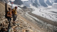 Ahli glasiologi Andreas Linsbauer dan asisten Andrea Millhaeusler berdiri di moraine perbatasan Gletser Pers dekat resor Alpine Pontresina, Swiss. Jika emisi gas rumah kaca terus meningkat, gletser Alpen diperkirakan akan kehilangan lebih dari 80% massanya saat ini pada tahun 2100.