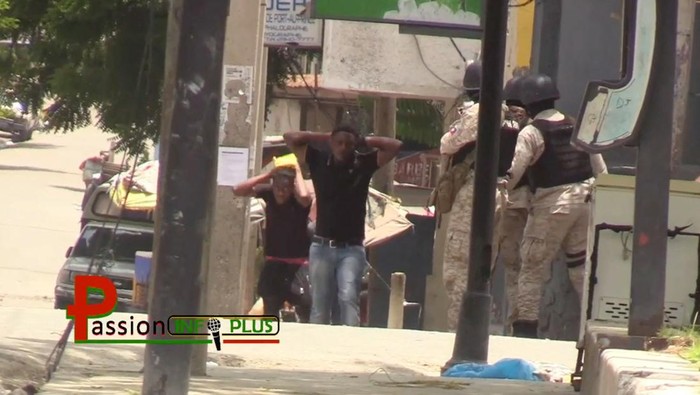 Gegara Perang Antar Geng, Warga Haiti Tinggalkan Ibu Kota People with hands behind their heads walk next to police officers patrolling the street in Port-au-Prince, Haiti, July 27, 2022, in in this still image obtained from social media video. Courtesy of Passion Info Plus/via REUTERS THIS IMAGE HAS BEEN SUPPLIED BY A THIRD PARTY. MANDATORY CREDIT. NO RESALES. NO ARCHIVES. DO NOT OBSCURE LOGO.