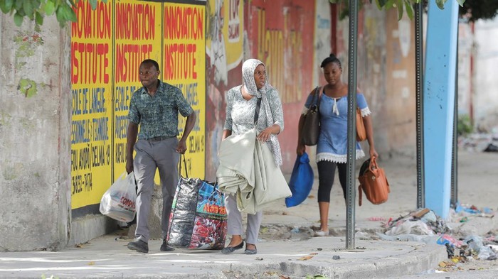 Gegara Perang Antar Geng, Warga Haiti Tinggalkan Ibu Kota People with hands behind their heads walk next to police officers patrolling the street in Port-au-Prince, Haiti, July 27, 2022, in in this still image obtained from social media video. Courtesy of Passion Info Plus/via REUTERS THIS IMAGE HAS BEEN SUPPLIED BY A THIRD PARTY. MANDATORY CREDIT. NO RESALES. NO ARCHIVES. DO NOT OBSCURE LOGO.